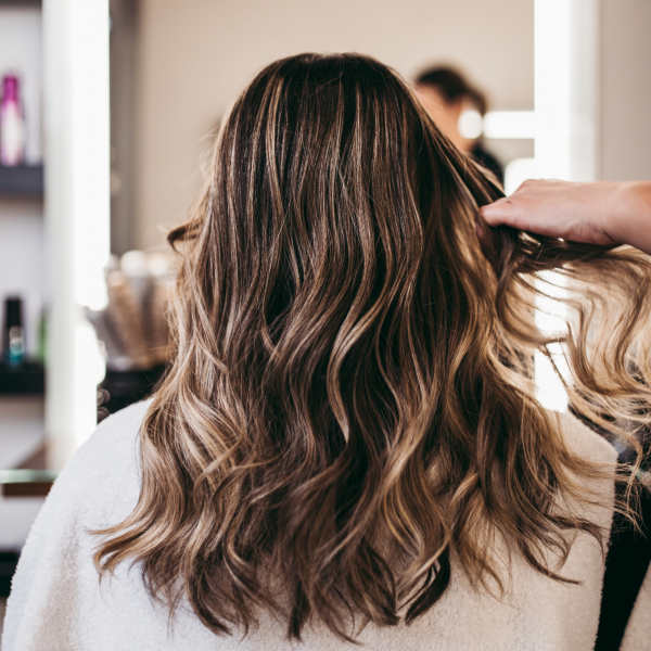 Beautiful brunette woman with long hair at the beauty salon getting a hair blowing. Hair salon styling concept.