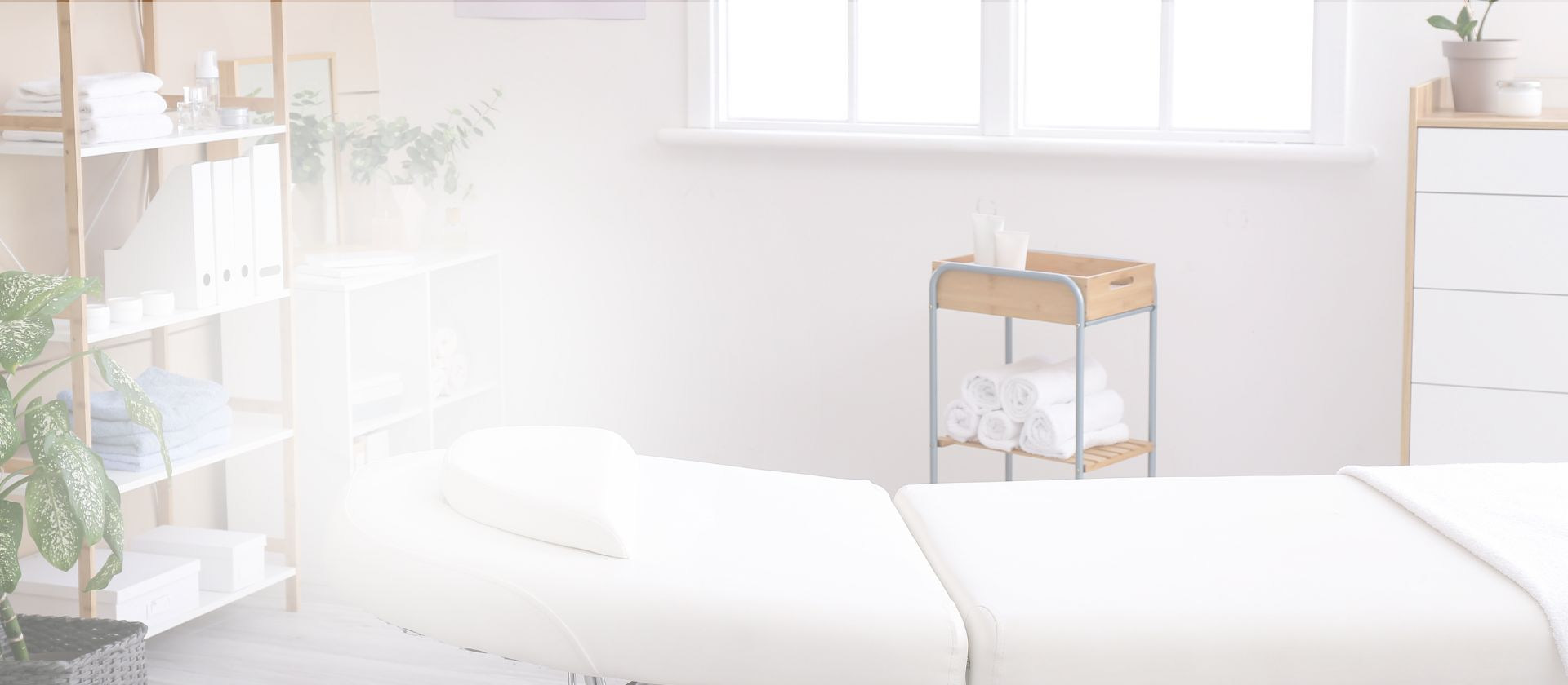 Bright, minimalist spa treatment room at Halcyon Cosmetic & Skin Studio in Port Moody featuring white massage beds, natural wood shelving with plants, and modern aesthetic
