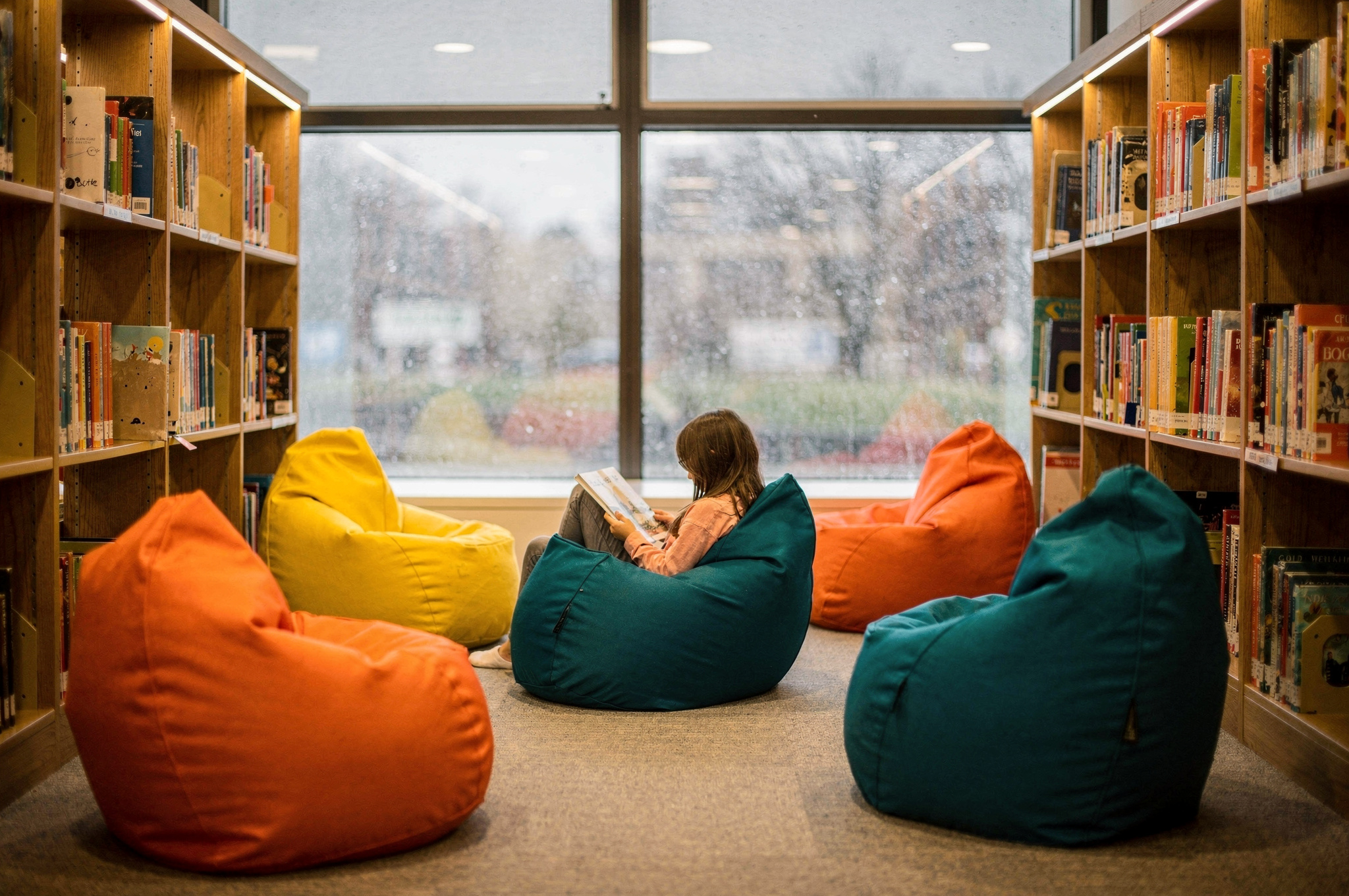 child reading in a library nook surrounded by colorful bean bag chairs