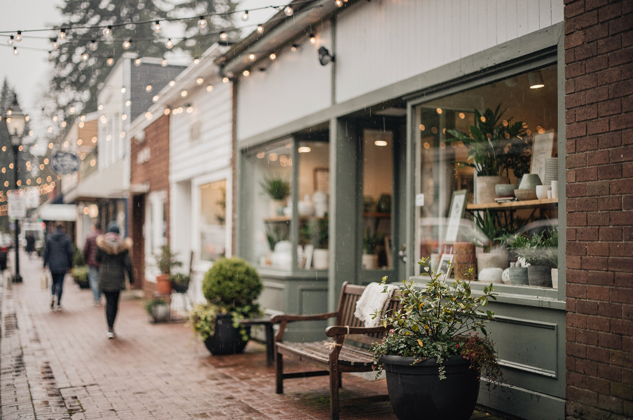 Independent shop storefronts along a Port Moody street with string lights and window displays