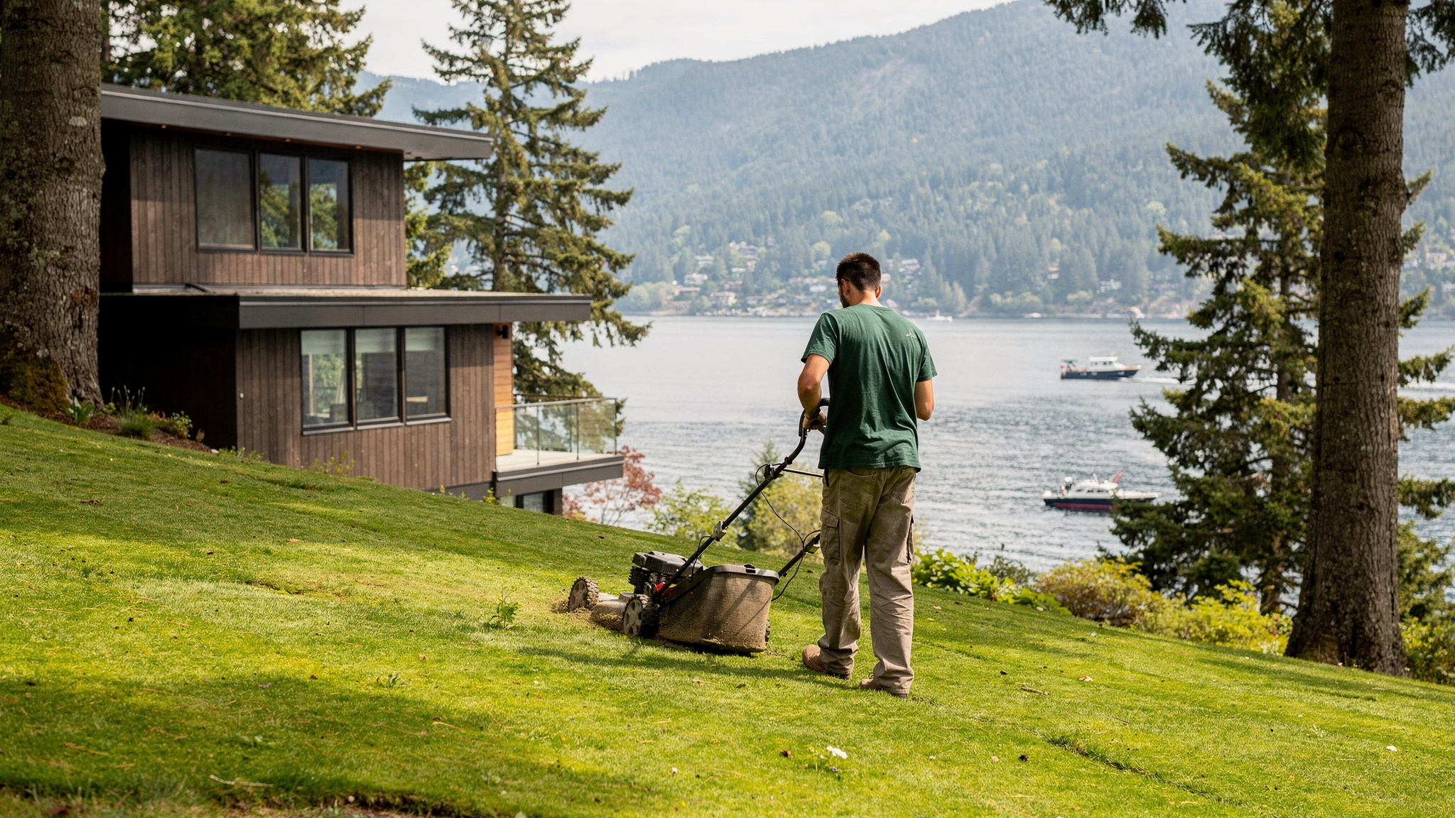 Port Moody BC landscaper mowing a waterfront lawn above Burrard Inlet